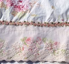 an embroidered piece of cloth with flowers on the edge and lace trimming around it