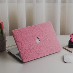 an apple laptop computer sitting on top of a desk next to a pink flower pot