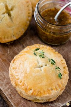 two pies on a cutting board next to a jar of sauce