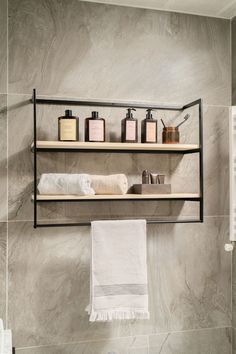 a bathroom with two shelves above the toilet and towels hanging on the wall next to it