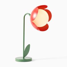 a red and white flower lamp sitting on top of a green table next to a white wall