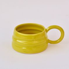 a yellow coffee cup sitting on top of a white table