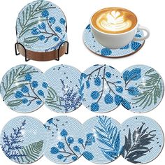 six blue and white plates with leaves on them, one has a cup of cappuccino