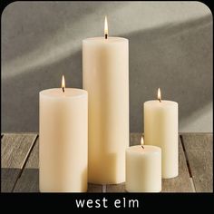 three white candles sitting on top of a wooden table