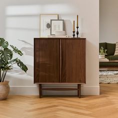 a wooden cabinet sitting next to a potted plant on top of a hard wood floor