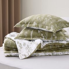 an unmade bed with green and white comforters