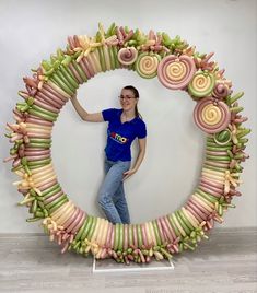 a woman is standing in front of a circular sculpture made out of doughnuts