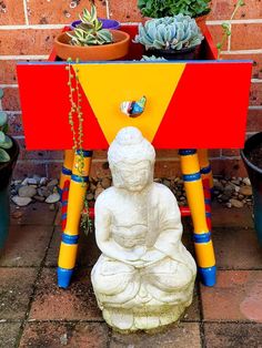 a small buddha statue sitting on top of a table next to succulents