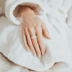 a woman's hand on top of a white blanket with a ring in it