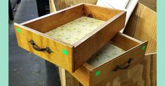 two drawers are open on the side of a wooden structure, with green and white fabric in them