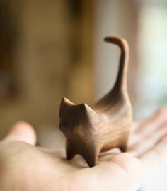 a wooden cat figurine sitting on someone's hand