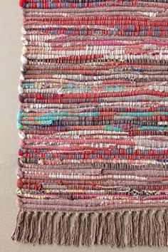 a multicolored rug with fringes on the bottom and one piece of fabric hanging from it