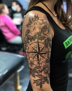 a woman with a compass and roses tattoo on her arm