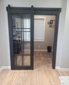 an empty room with wooden floors and sliding glass doors that lead into the living area