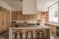 a large kitchen with wooden cabinets and stools