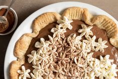 there is a pie on the plate with chocolate sauce and sprinkles around it