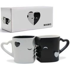 two black and white coffee mugs with faces drawn on them, next to a box