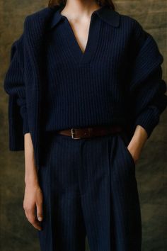 a woman wearing a blue sweater and wide legged pants with her hands in her pockets