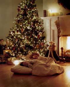 a christmas card with an image of two children laying in bed under a lit tree