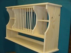 a wooden shelf with two open shelves on it's sides, against a blue wall