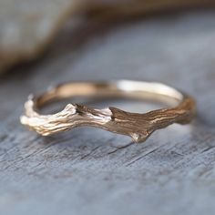 a close up of a gold ring on top of a piece of wood with a tree branch in the middle