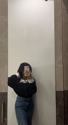 a woman taking a selfie in front of a mirror with her cell phone up to her face