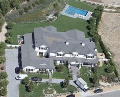 an aerial view of a large house with a pool in the middle and lots of trees around it