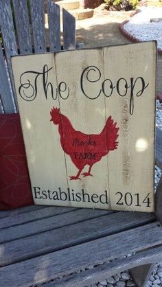 a wooden sign that says the coop on it sitting on a bench next to a red pillow