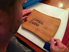 a man holding a wooden cutting board with writing on it