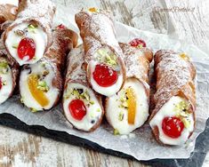 several pastries with fruit and nuts are on a piece of wax paper, ready to be eaten