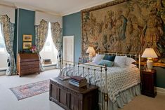 a bed room with a neatly made bed and a large tapestry hanging on the wall