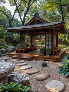 a small wooden gazebo surrounded by rocks and plants in a garden area with trees