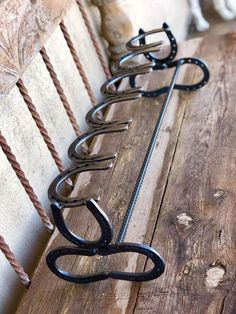 four wrought iron hooks hang on the side of a wooden bench