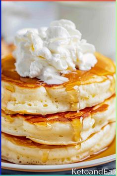 stack of pancakes topped with whipped cream and syrup