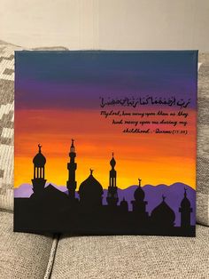 a painting on a couch with the words in arabic and an image of a mosque at sunset