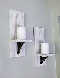 two white candle holders are on the wall