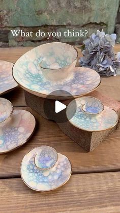 a table topped with lots of plates on top of a wooden table next to flowers