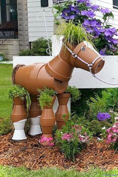 a horse shaped planter in the middle of a flower bed with purple flowers growing out of it