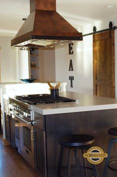 a kitchen with two stools next to an oven and stove top island in the middle