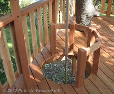 a wooden deck with a tree in the middle and a circular bench on it's side