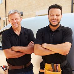 two men standing next to each other in front of a car with their arms crossed