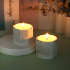 two white candles sitting on top of a table