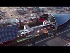 an aerial view of a train station with solar panels on the roof and cars in the background