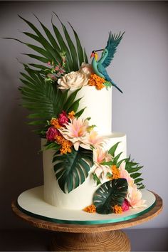 a three tiered cake decorated with tropical leaves and flowers