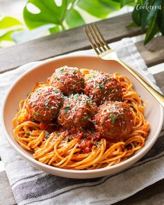 spaghetti with meatballs and parmesan cheese in a white bowl on a wooden table