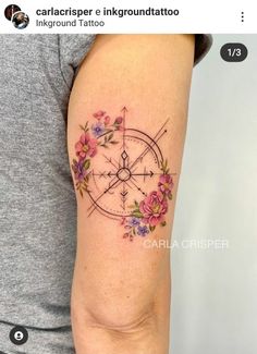 a woman's arm with flowers on it and a compass in the middle of her arm