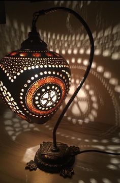 a lamp that is sitting on top of a wooden table next to a shadow wall