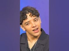 a young man making a funny face while wearing a black shirt and silver chain necklace