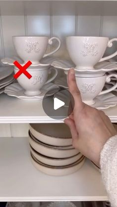 a person is pointing at dishes on the shelves