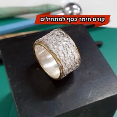 a silver ring sitting on top of a wooden block